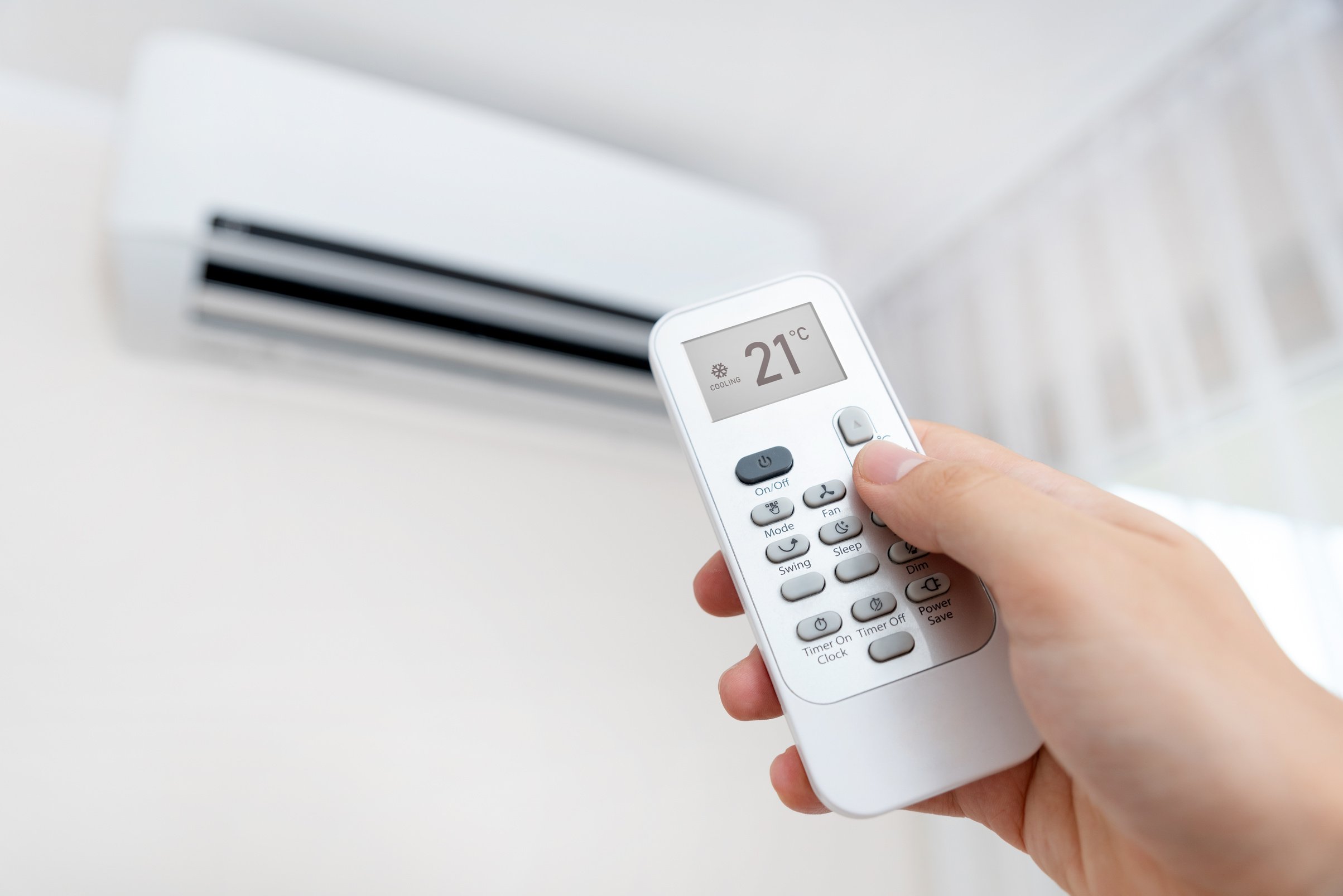 Hand with Remote Directed on Air Conditioner.